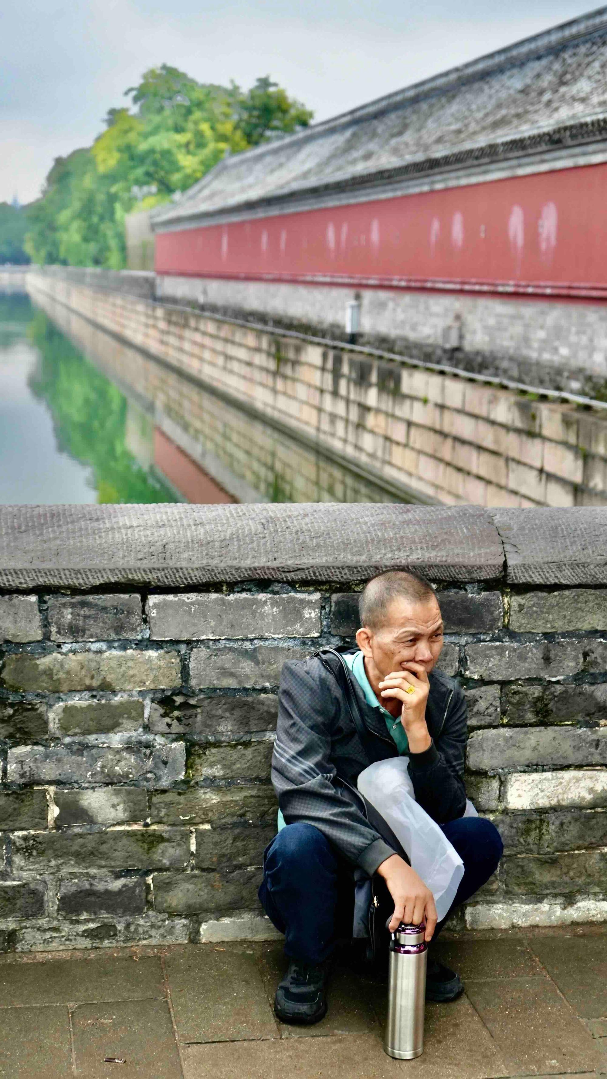 A worker rests in the bridge across the Forbidden City moat